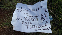Cartaz deixado ao lado de corpo encontrado na fronteira (Foto: Rádio Oásis)