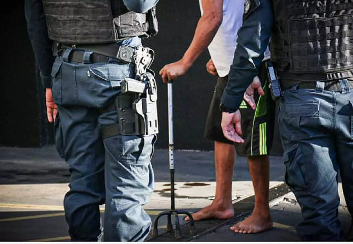 Homem de bengala chegou escoltado na 1ª DP. Imagem: (Henrique Kawaminami)